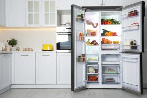 Open refrigerator filled with food in kitchen